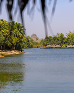 View of the Green Cathedral river loop with lush palm trees and traditional thatched huts along the banks in Kampot, Kampot Province, Cambodia.
