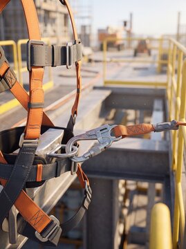 Safety harness with carabiner attached to a metal structure at a construction site. Vertical video orientation. Orange fall protection equipment for high altitude industrial workers