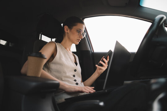 Businesswoman using smartphone and working in car