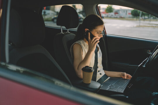 Businesswoman talking on phone and working in parked car