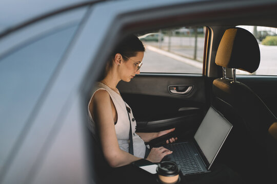 Businesswoman working from back seat