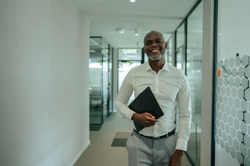 Fototapeta premium Confident mature businessman holding folder walking office hallway