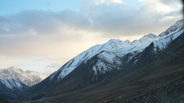 Snow capped mountain range at dusk with golden clouds in Kaghan Pakistan