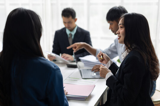 Business colleagues collaborating during a professional office meeting. Asian business people working together in office workplace, teamwork and cooperation.