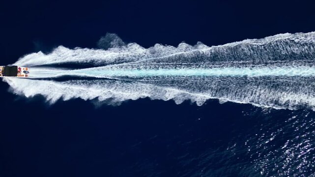 A boat speeds across the adriatic sea, creating a stunning wake against the deep blue water. The scene represents a summer vacation, highlighting the thrill of travel and the allure of the coastline.