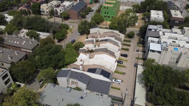Stepped townhouse rooflines flank private paved driveways along Congress Avenue in Dallas. Dark solar panels showcase contemporary clean energy updates across DFW Metroplex, Texas