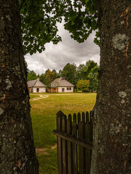 Rural Countryside Wooden Cottages Framed by Trees and Gate