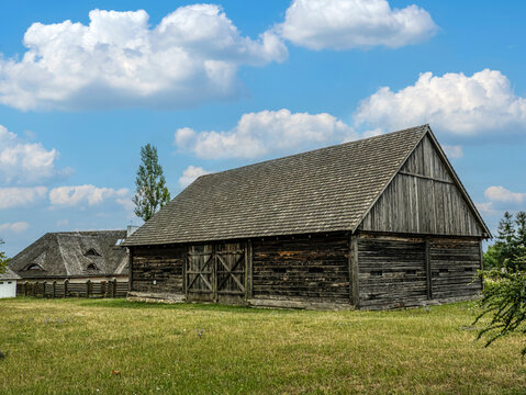 Rustic Wooden Barn in Sunny Countryside Meadow Under Blue Sky With Puffy Clouds