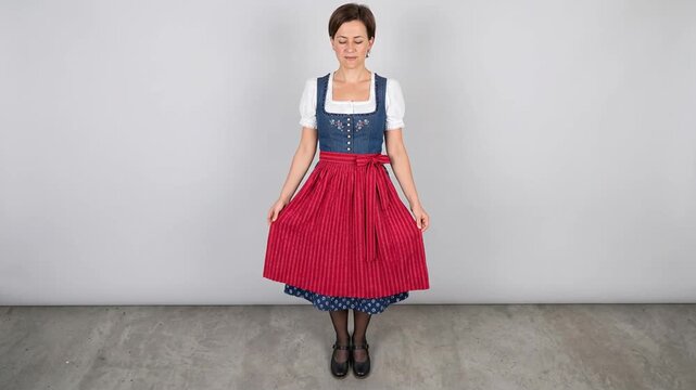 Woman wearing traditional folk dress standing against a light grey studio background