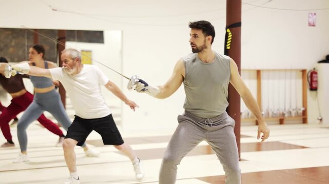 Athletic people train in a fencing class, they confidently hold a rapier in their hands and practice movements. High quality 4k footage