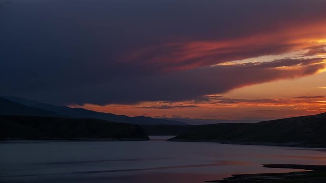 A dramatic sunset over a calm mountain lake with colorful purple and orange clouds. Commercial background for mindfulness, travel advertising, premium tranquility and nature wellness concepts with cop