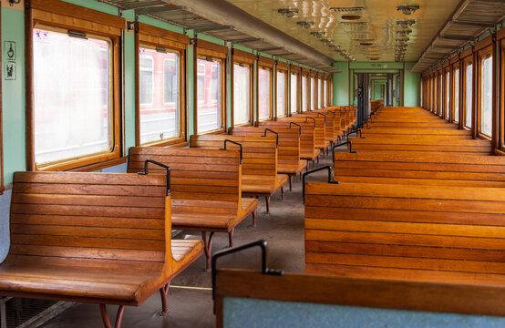 View of the interior of a vintage train carriage with rows of wooden benches and large windows at the Railway Park in Vilnius, Vilniaus apskritis, Lithuania.