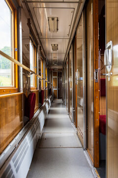 View of the interior corridor of a vintage train carriage with wooden paneling, red upholstered seats, and large windows in Railway Park, Vilnius, Vilniaus apskritis, Lithuania.