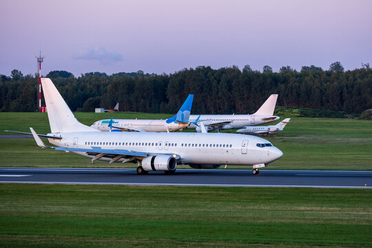 View of a white passenger airplane taxiing on the runway at Vilnius International Airport with other aircraft parked in the background at Vilnius, Vilniaus apskritis, Lithuania.