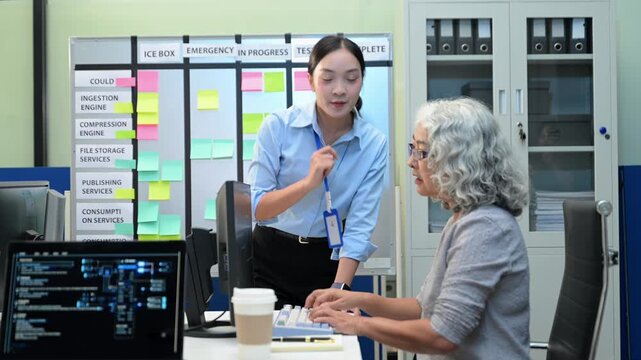 Asian software developers and engineers planning workflow on an agile scrum board with sticky notes