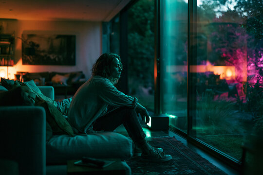 Lonely Person Sitting on Sofa Looking Out Window at Night