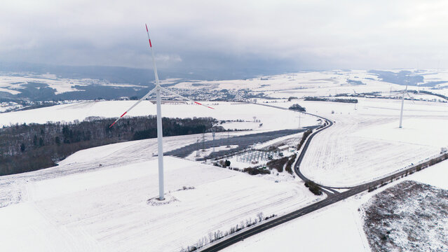 Windless wind turbine in snow, dark doldrums or wind lull in winter, renewable sustainable energy, environmental conversation, Germany