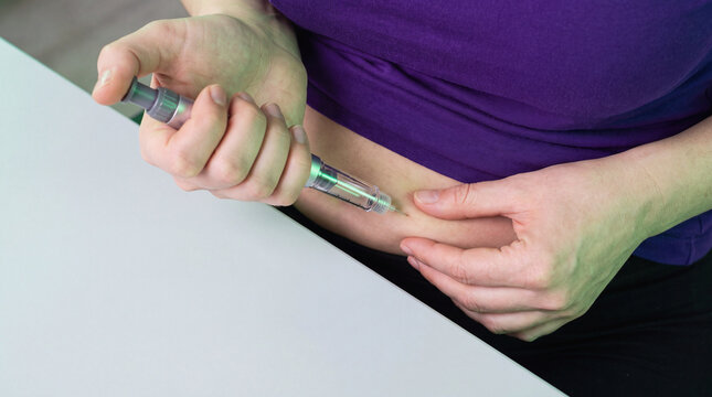 Woman self-administering GLP-1 injection pen into abdomen for weight loss control