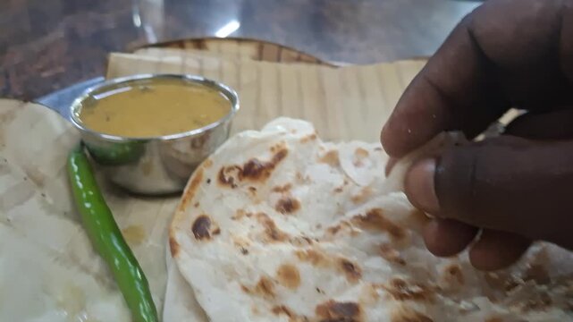 Indian flatbread such as parota or naan served with flavorful gravy in a small bowl, representing traditional South Asian cuisine and delicious dining