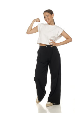 Full length fashion portrait of confident woman flexing arm muscles, strong pose, on white background.