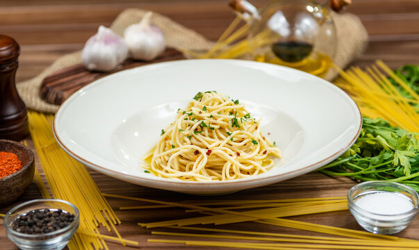 Spaghetti with garlic, olive oil and fresh herbs, restaurant pasta, side view on a rustic wooden table
