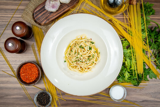 Spaghetti with garlic, olive oil and fresh herbs, food flat lay, top-view on a rustic wooden table