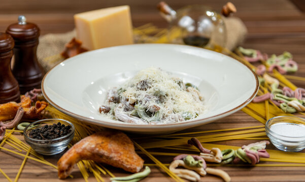 Creamy wild mushroom pasta topped with parmesan cheese, restaurant main course, side view on a rustic wooden table