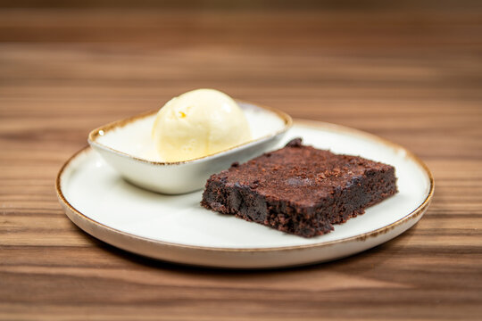 Chocolate brownie served with vanilla ice cream, restaurant dessert, side view on a wooden table