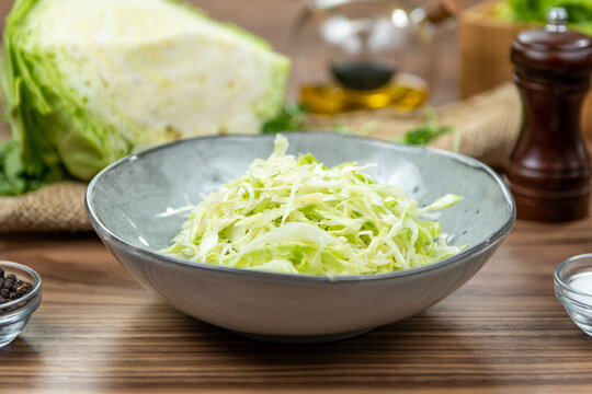 Fresh coleslaw salad with shredded cabbage served in a gray bowl, restaurant side dish, side view on a rustic wooden table
