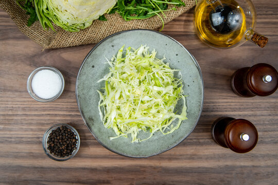 Coleslaw salad with shredded cabbage served in a gray bowl, food flat lay, top-view on a rustic wooden table