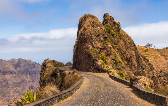 View of the winding cobblestone road passing through the dramatic rocky cliffs of Topo da Montanha do Delgadinho in Santo Antao, Corda, Ribeira Grande, Cabo Verde.