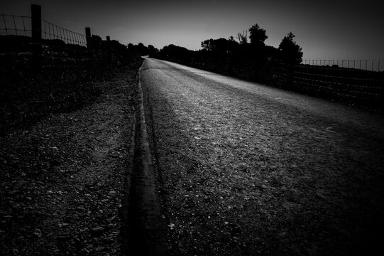 Black and white image of a road in a rural area, with strong contrast, dike landscape on the Hunte in summer in 27798 Hude, Germany