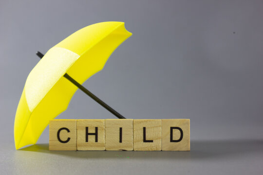 Yellow umbrella protecting notes labeled CHILD, representation bullying, and child abuse, pedophile, symbolizing child protection, safety, insurance, education, emotional support, and building a secur