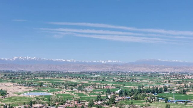 Aerial Time-lapse of Rural Landscape with Distant Qilian Snow Mountains Under Blue Sky,Wuwei city, Gansu province, China.