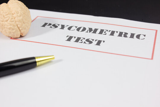 Pen, miniature brain, and paper labeled PSYCHOMETRIC TEST, symbolizing job assessments, psychological testing, cognitive evaluation, personality analysis, recruitment, employee selection, and career d