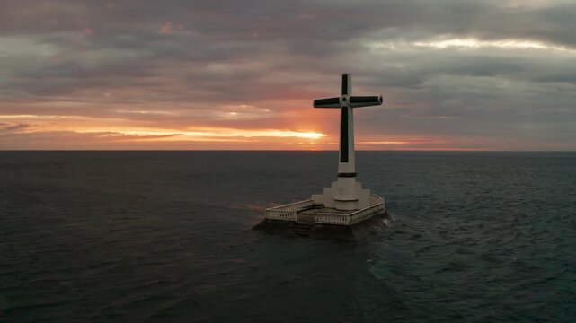 Catholic cross in sunken cemetery in the sea at sunset, aerial view. Colorful bright clouds during sunset over the sea. Sunset at Sunken Cemetery Camiguin Island Philippines.