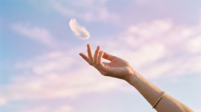 Female hand releasing a white feather into the blue sky with clouds, symbolizing freedom, peace, lightness, letting go, spirituality, hope, and dreams, capturing a moment