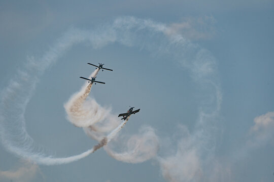 View of Team Raven performing aerobatic maneuvers with Van's RV-8 aircraft leaving smoke trails in the sky during the Antidotum Airshow in Leszno, Greater Poland Voivod, Poland.