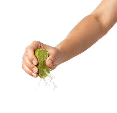 Hand squeezing fresh lime half with juice splashing on transparent background isolated close up