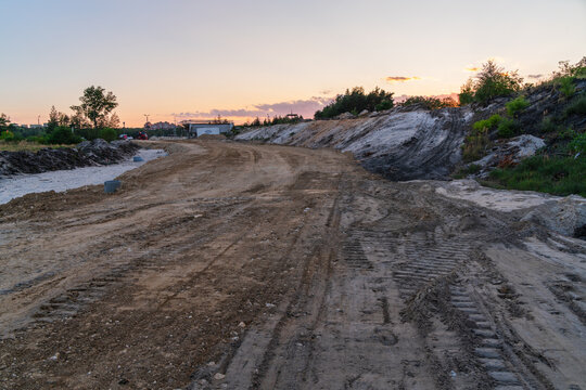 Jaworzno, Poland - 23 August 2026: View of a dirt road under construction with tire tracks and uneven terrain at sunset in the Silesian Voivodeship.