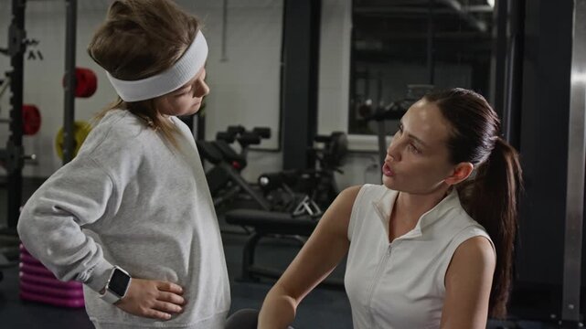 Caucasian female trainer instructing Caucasian boy during gym workout, guiding him through neck stretching exercises. Perfect for promoting youth fitness programs or personal training services