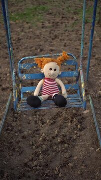 Plush Girl Doll on Aged Playground Swings in a Park Vertical Frame