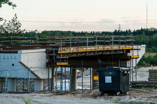 Jaworzno, Poland - 23 August 2026: View of a bridge under construction with concrete pillars, scaffolding, and metal railings at a development site.