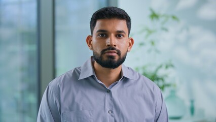 Fototapeta premium Portrait serious Arabian businessman looking at camera confident Muslim business man work posing in modern office focused Hindu male guy professional manager executive agent look working in company