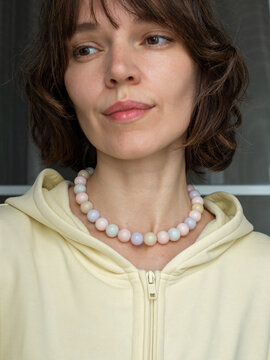 Portrait of brown hair woman wearing quartz stone jewelry necklace - warm neutral aesthetic with natural beauty style