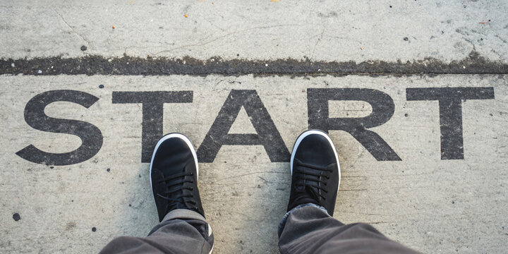 Starting over and starting a business with your foot standing behind the word START painted on the concrete floor.