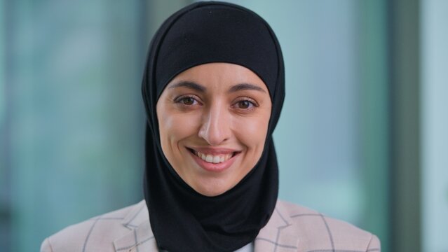 Portrait happy positive Arabian ethnic Muslim business woman smiling toothy looking at camera Indian female Islamic businesswoman wearing hijab cheerful girl office manager smile optimistic posing