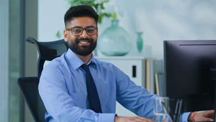 Fototapeta premium Happy Muslim business man Arabian male typing computer smiling looking at camera in office worker Indian businessman male productive executive specialist working with desktop work smile satisfied