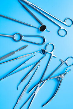 A lot of stainless surgical instruments and tools on blue table, top view. Medical background