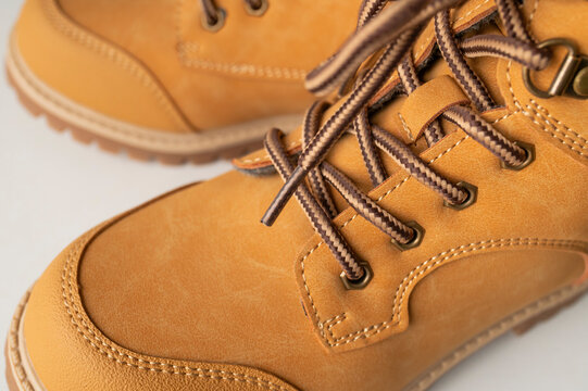 Tan leather boots with dark laces fill frame in detailed close-up on light gray background. Rugged footwear, sturdy soles and durable construction support autumn fashion and product advertising.